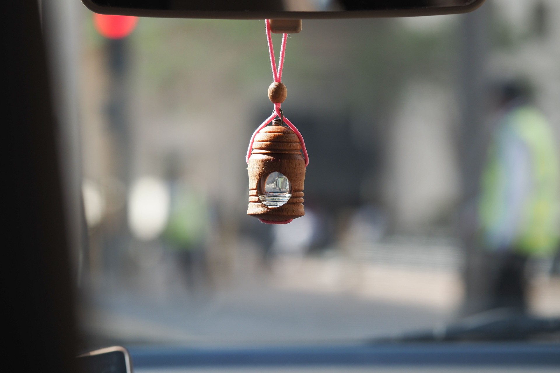 Wooden charm hanging from car rearview mirror in traffic